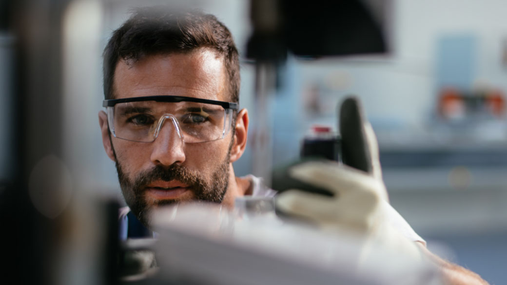 Close-up of engineer wearing protective glasses using machine
